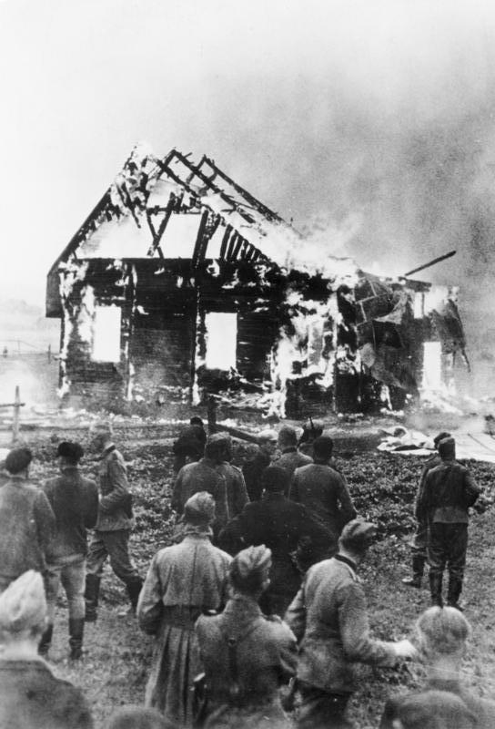 Scherl: Von Litauern in Brand gesteckte Synagoge.  Die Erbitterung gegen die jüdischen Verbrecher ist in den baltischen Ländern besonders groß, denn gerade die Juden waren es, die der GPU zahllose unschuldige Opfer in die Hände spielten und der Ermordung oder Verbrennung auslieferten. PK - Zoll - Scherl.  9.7.41 [Herausgabedatum] AV 64149 "Fr" OKW ADN-Bildarchiv: II. Weltkrieg 1939-45 In einem litauischen Ort beobachten Soldaten der faschistischen deutschen Wehrmacht und Einheimische das Niederbrennen einer angezündeten Synagoge. Aufnahme: Zoll/Juni 1941